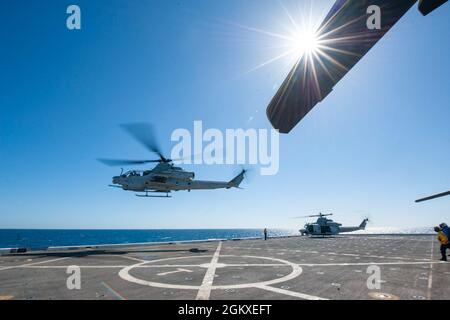 210718-N-XB010-1015 CORALLO MARE (18 luglio 2021) Un corpo marino americano AH-1Z Cobra, primo piano, e UH-1Y Huey elicottero decollo dal ponte di volo USS New Orleans (LPD 18) in preparazione all'arrivo del Cap. Greg Baker, Commodore, Amfibio Squadron 11, E il col. Michael R. Nakonieczny, comandante della 31esima unità di spedizione marina (MEU). New Orleans, parte dell'America Expeditionary Strike Group, insieme al 31° MEU, sta operando nell'area di responsabilità della settima flotta statunitense per migliorare l'interoperabilità con alleati e partner e servire come una forza di risposta pronta a difendere p Foto Stock