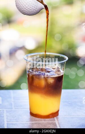 Preparazione del caffè Bumble - rinfrescante cocktail estivo ghiacciato con espresso, succo d'arancia, sciroppo di caramello e ghiaccio Foto Stock