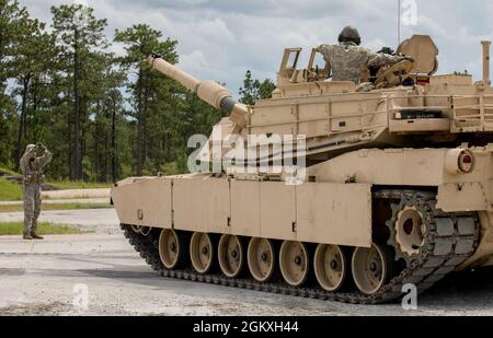 Un Master Gunner studente dell'esercito degli Stati Uniti, assegnato al 3rd Squadron, 16th Calvary Regiment, usa i segnali di mano e di braccio per dirigere un M1A2 SEP V2 Abrams Tank dove muoversi a Ware Range, Fort Benning, GA., 20 luglio 2021. Queste petroliere si stanno allenando per diventare Mater Gunners, ed essere esperti in materia nel loro campo. Foto Stock