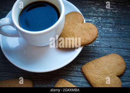 Caffè bianco con bevande calde fresche e biscotti di pan di zenzero a forma di cuore. Pausa caffè con amore. Lato della tazza di caffè con bevanda calda. Fatto in casa Foto Stock