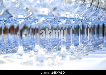 Molti bicchieri di cristallo puliti su tovaglie bianche preparati per grandi feste. Sfocato. Servizio catering e utensili da ristorante. Organizzazione di matrimoni. Vino Foto Stock