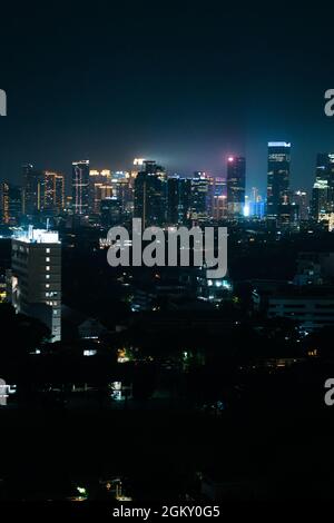 GIACARTA, INDONESIA - 07 luglio 2021: Uno scatto verticale di uno skyline di Jakarta Indonesia di notte con una vista di impressionanti luci al neon Foto Stock