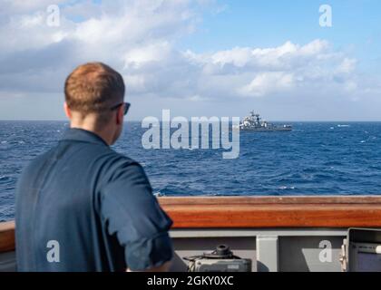 210722-N-UT641-0001 BAIA DEL BENGALA (22 luglio 2021) comandante del cacciatorpediniere missilistico guidato di classe Arleigh Burke USS i Sullivans (DDG 68) CMdR. David L. Burkett osserva come il cacciatorpediniere della classe Rajput della Marina indiana IN Ranvir (D54) passa vicino, 22 luglio 2021. USS il Sullivans è attualmente legato al Carrier Strike Group del Regno Unito, che opera nella 7a flotta a sostegno della prosperità reciproca condivisa e di un libero e aperto Indo-Pacific. Foto Stock