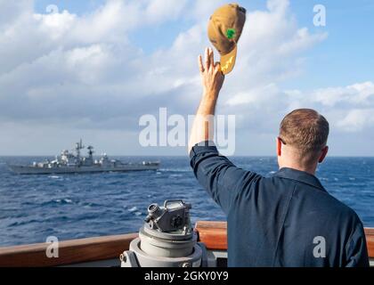 210722-N-UT641-0003 BAY OF BENGALA (22 luglio 2021) comandante del cacciatorpediniere missilistico guidato di classe Arleigh Burke USS i Sullivans (DDG 68) CMdR. David L. Burkett ondeggia il suo cappello al cacciatorpediniere della classe Rajput della Marina indiana IN Ranvir (D54) passa vicino, 22 luglio 2021. USS The Sullivans è attualmente collegato al Regno Unito HMS REGINA ELIZABETH Carrier Strike Group, che sta operando in 7th Fleet sostenendo la prosperità condivisa reciproca e un libero e aperto Indo-Pacific. Foto Stock