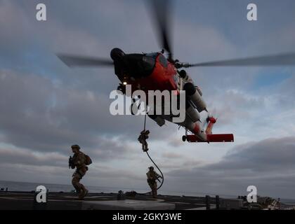 Coast Guard Maritime Security Response Team-West membri veloce-corda di un MH-60J Jayhawk sulla Cutter Munro Guardia Costiera durante le operazioni di volo al largo della costa di San Diego, California, 23 luglio 2021. Il Cutter Munro della Guardia Costiera ha condotto addestramento di funzionamento di volo con la Marina degli Stati Uniti e il team di risposta di sicurezza marittima-ovest per mantenere le abilità operative. Foto Stock