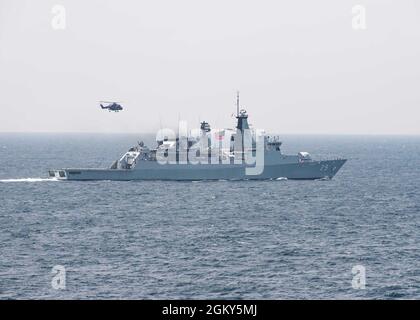 210725-N-UT641-0002 SOUTH CHINA SEA (25 luglio 2021) Un elicottero Royal Navy AW159 Wildcat vola sulla Royal Navy malese Lekiu-class missile fregate KD Jebat (FFG29) durante un esercizio fotografico con il Carrier Strike Group del Regno Unito Foto Stock