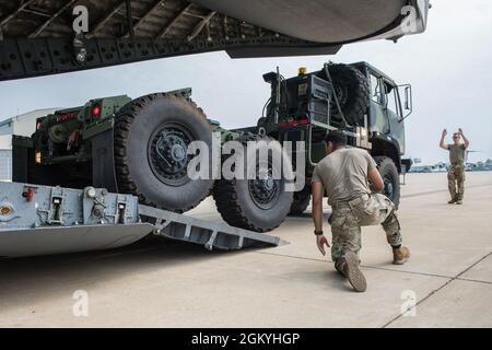 US Air Force Airman 1a classe Nathaniel Catrow, un loadmaster con il 167th Operations Group, marshalls un M1088 trattore camion dalla 1528th Forward Support Company, Special Operations (Airborne), West Virginia National Guard, Sulla rampa di un aereo C-17 Globmaster III con la 167a Ala Airlift come parte di un esercizio di addestramento di carico alla base della Guardia Nazionale aerea di Shepherd Field, Martinsburg, West Virginia, 29 luglio 2021. Questo esercizio di formazione ha dimostrato l'interoperabilità della forza comune e la capacità di dispiegare rapidamente truppe e carichi in un ambiente di missione comune. Foto Stock