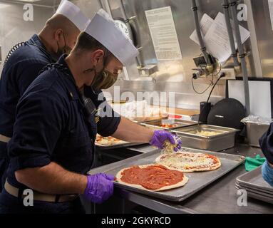 OCEANO PACIFICO (lug. 31, 2021) i membri del pasticcio del capo ufficiale preparano la pizza per l’equipaggio delle navi in cucina a bordo della nave da combattimento litoranea variante Indipendenza USS Jackson (LCS 6). La nave da combattimento Littoral Combat Ship (LCS) è una piattaforma veloce, agile e mirata alla missione progettata per operare in ambienti vicino alla costa, vincendo contro le minacce costiere del XXI secolo. La LCS è in grado di sostenere la presenza in avanti, la sicurezza marittima, il controllo marittimo e la deterrenza. Foto Stock