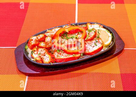 Vassoio di Tikka di pollo con spiedini, con peperoni rossi, cipolle bianche e limone con prezzemolo Foto Stock