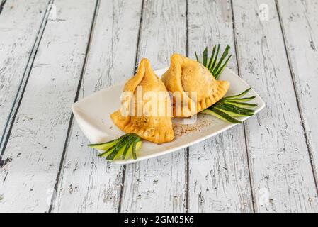 Porzione di samosa farcita di verdure servita in un ristorante pakistano in europa su un tavolo bianco Foto Stock