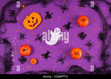 Cornice di Halloween con zucche, fantasmi e ragni su sfondo viola. Copia spazio per il testo. Concetto di halloween. Foto Stock