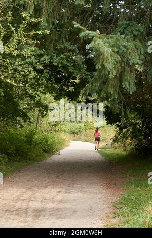 Donna jogging lungo un percorso attraverso una zona boscosa Foto Stock