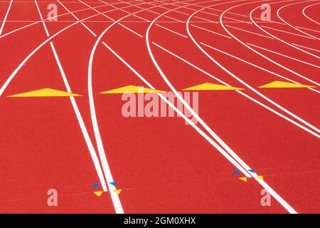 Linee bianche, triangoli gialli e segni di ostacolo sulla curva della pista di corsa in gomma per tutte le condizioni meteorologiche. Foto Stock