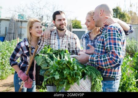 Famiglia felice di quattro giardinieri che tengono raccolto di verdure e di verdi Foto Stock