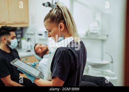 Femmina caucasica che digita su tablet digitale preparazione appuntamento con il cliente maschile Foto Stock