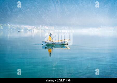 Pesca del pescatore in una mattina di nebbia. Ubicazione: Kotor, Baia di Boka, Montenegro. Una foto di un pescatore di mattina presto in inverno. Foto Stock