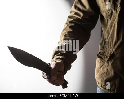 Uomo che tiene un machete nel suo e in una posizione minacciosa Foto Stock