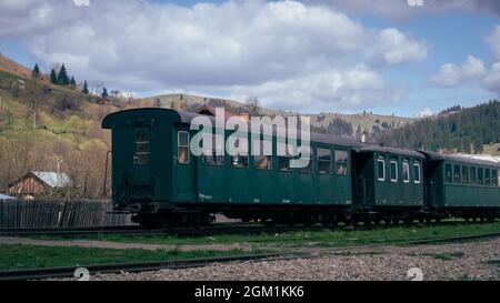 MOLDOVITA, ROMANIA - 04 maggio 2021: Un colpo verticale del vecchio treno a vapore e della ferrovia di Mocania in Moldovita, Romania Foto Stock