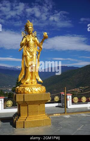 Una graziosa statua della dea dorata si erge sulla terrazza superiore intorno alla statua del Buddha Dordenma nel parco naturale Kuensel Phodrang vicino a Thimphu Bhutan Foto Stock