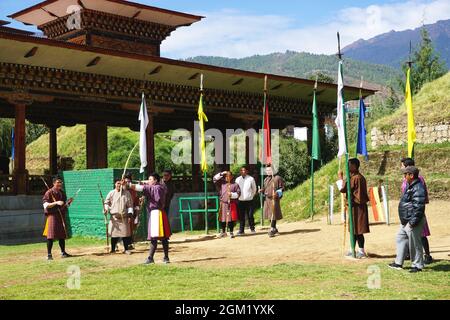 Gli arcieri bhutanesi attendono il loro turno mentre un membro del team si allinea al suo prossimo colpo a Thimphu, Bhutan. Il tiro con l'arco è lo sport nazionale del Regno del Bhutan. Foto Stock