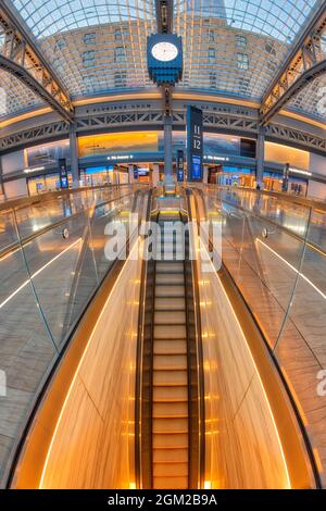 Moynihan Train Hall NYC - Vista scala mobile dorata della stazione ferroviaria recentemente rinnovata nel centro di Manhattan a New York City. Con le parole e pluribus Foto Stock