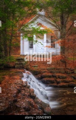 Cascade and Chapel - le foglie del fogliame autunnale coprono i terreni che circondano questo pittoresco Chapel e Cascade presso l'Hickory Tun state Park in Pennsylvania. THI Foto Stock