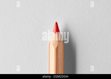 Matita in pastello di legno rosso su sfondo bianco. Vista macro ravvicinata con spazio di copia. Foto Stock