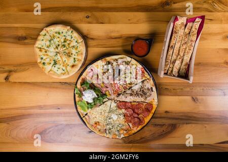 Diversi tipi di pizza combinati in una con salsa di pomodoro, panini e pane per pizza Foto Stock