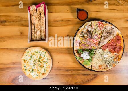 Diversi tipi di pizza combinati in una con salsa di pomodoro, panini e pane per pizza Foto Stock