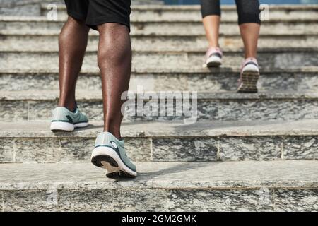 Primo piano dei giovani in scarpe sportive che si muovono sulle scale mentre si allenano all'aperto Foto Stock