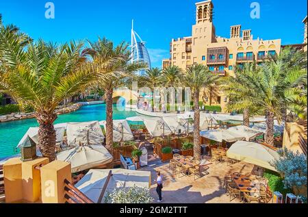 Il complesso Souk Madinat Jumeirah vanta vicoli verdi con palme ombreggiate lungo i canali, ristoranti all'aperto, piccoli ponti ed edifici tradizionali. Foto Stock