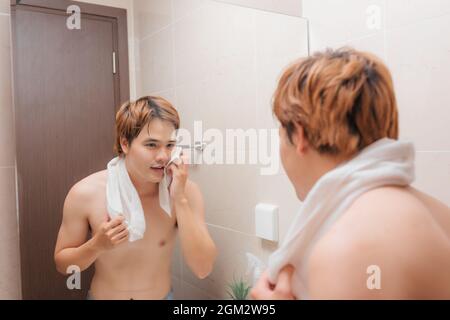 Giovane uomo faccia di essiccazione con asciugamano come parte della quotidiana routine di igiene Foto Stock