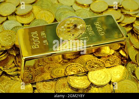 Criptovaluta Bitcoin sulla barra d'oro e pila di monete d'oro Foto Stock