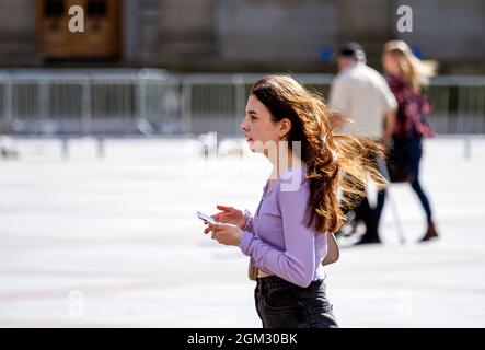 Dundee, Tayside, Scozia, Regno Unito. 16 settembre 2021. Tempo britannico: Caldo sole a metà settembre in tutta la Scozia nord-orientale con temperature che raggiungono i 19°C. Una giovane donna che trascorre la giornata godendosi il caldo clima di sole mentre parla sul suo telefono cellulare nel centro di Dundee. Credit: Dundee Photographics/Alamy Live News Foto Stock