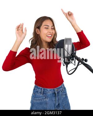 Giovane donna asiatica in t-shirt rossa danza, ondeggiare, e sollevare le braccia ritmicamente mentre cantano con microfono su sfondo bianco. Produttore musicista Foto Stock