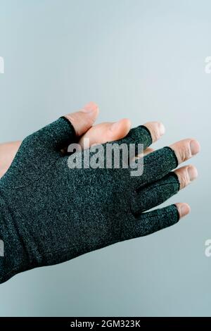 primo piano di un uomo caucasico indossare o togliere un guanto di compressione su uno sfondo bianco con un po' di spazio vuoto sulla parte superiore Foto Stock