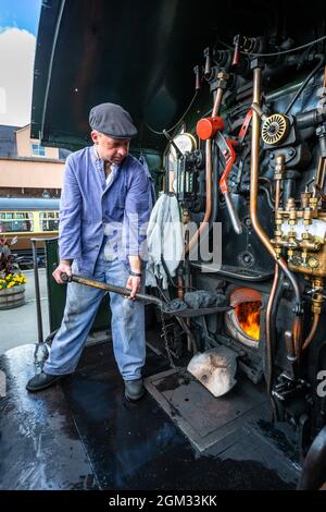 Kidderminster, Worcs, Regno Unito. 16 settembre 2021. Il pilota del motore Dave Ward tende il fuoco del suo luogo di vapore alla stazione ferroviaria di Severn Valley, Kidderminster, il giorno di apertura del Severn Valley Railway's Autumn Steam Gala, Kidderminster, Worcestershire. Il volontario SVR Dave Ward è normalmente visto guidare i treni CrossCountry nel suo lavoro a tempo pieno. Il gala dura fino a domenica 19 settembre e dispone di locos per gli ospiti. Peter Lopeman/Alamy Live News Foto Stock