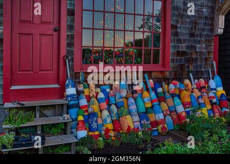 Natale a Rockport ME - file di boe colorate allineate in un negozio con motivo numero uno con un albero di Natale illuminato all'interno di Bradley Wharf Foto Stock