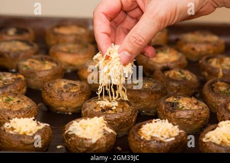 Cottura di funghi con formaggio. Cottura di champignons ripieni di formaggio nel forno elettrico Foto Stock