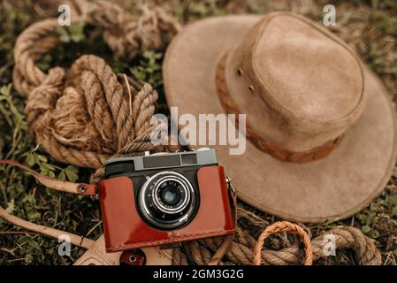 Primo piano di una macchina fotografica vintage, corde e un cappello marrone a terra Foto Stock