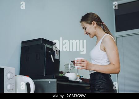Cura dei dipendenti, cura sul posto di lavoro, coinvolgimento e fidelizzazione. Giovane donna d'affari che beve caffè nella sala delle pause d'ufficio durante l'ora di pranzo Foto Stock