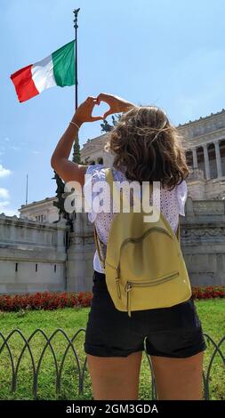 Gesto fatto con le mani che mostra il simbolo del cuore e dell'amore sulla bandiera nazionale italiana. Donna che mostra il suo amore per la bandiera italiana. turista a roma Foto Stock