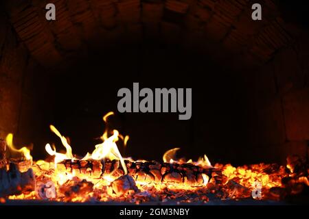 Scintille calde rosse che bruciano volano dal fuoco grande. Bel sfondo astratto sul tema del fuoco. Carboni brucianti, particelle infiammate che volano contro la colpa Foto Stock