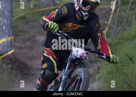 Una giovane discesa in mountain bike che scende su un terreno difficile in boschi Foto Stock