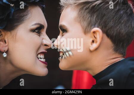 vista laterale di madre e figlio in grinning spooky del trucco a vicenda Foto Stock