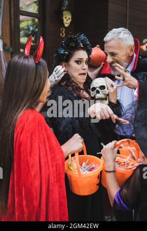 famiglia in costumi di halloween, con secchielli di dolci, madre spaventosa paura Foto Stock