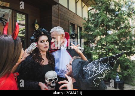 i bambini in costumi di halloween spaventano la mamma spaventata vicino al padre sorridente Foto Stock