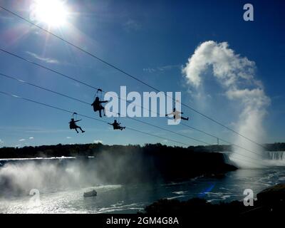 Cascate del Niagara, Ontario, Canada - 19 ottobre 2016: Quattro avventurosi visitatori fanno un giro in zipline verso le cascate Horseshoe in una splendida giornata di ottobre Foto Stock