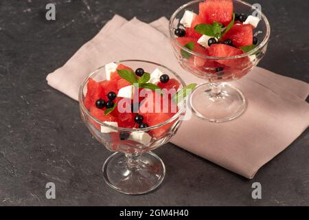 Insalata biologica estiva con cocomero, formaggio feta, ribes nero e menta. Colazione dietetica leggera. Messa a fuoco selettiva. Foto Stock