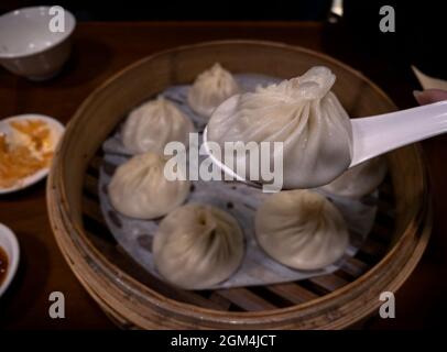 Tuffando gnocchi in ristorante asiatico. Mangiate il tradizionale cibo cinese servito in dim sum a Taiwan. Preparato come piccole porzioni mordenti di cibo serv Foto Stock